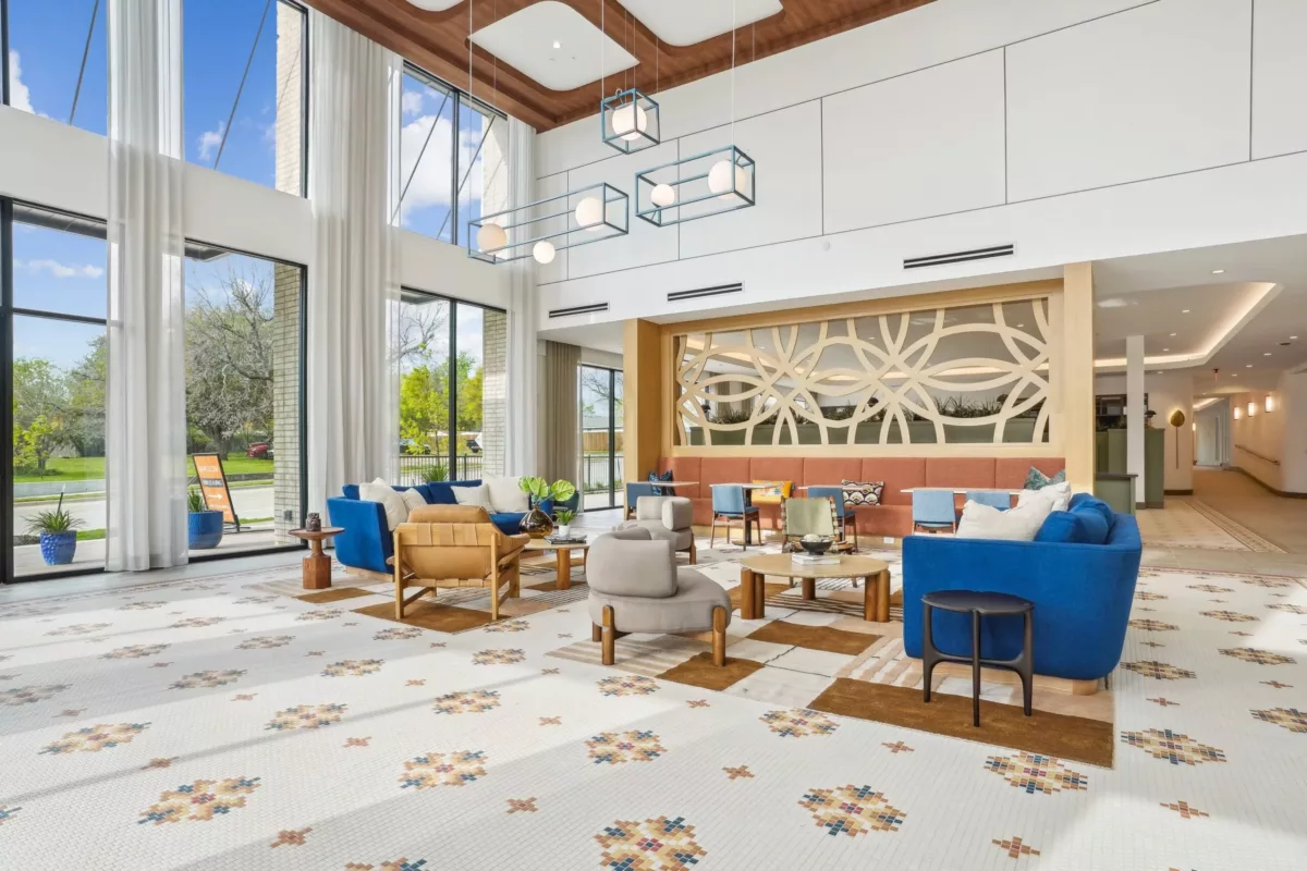 Lobby with two-story windows, tile floors with floral designers, and armchairs for seating