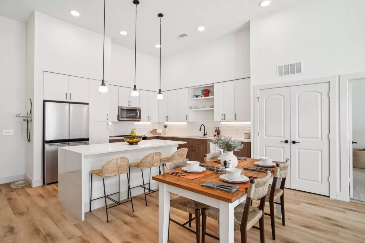 Kitchen with white and brown cabinets, center island, and hanging pendant lights