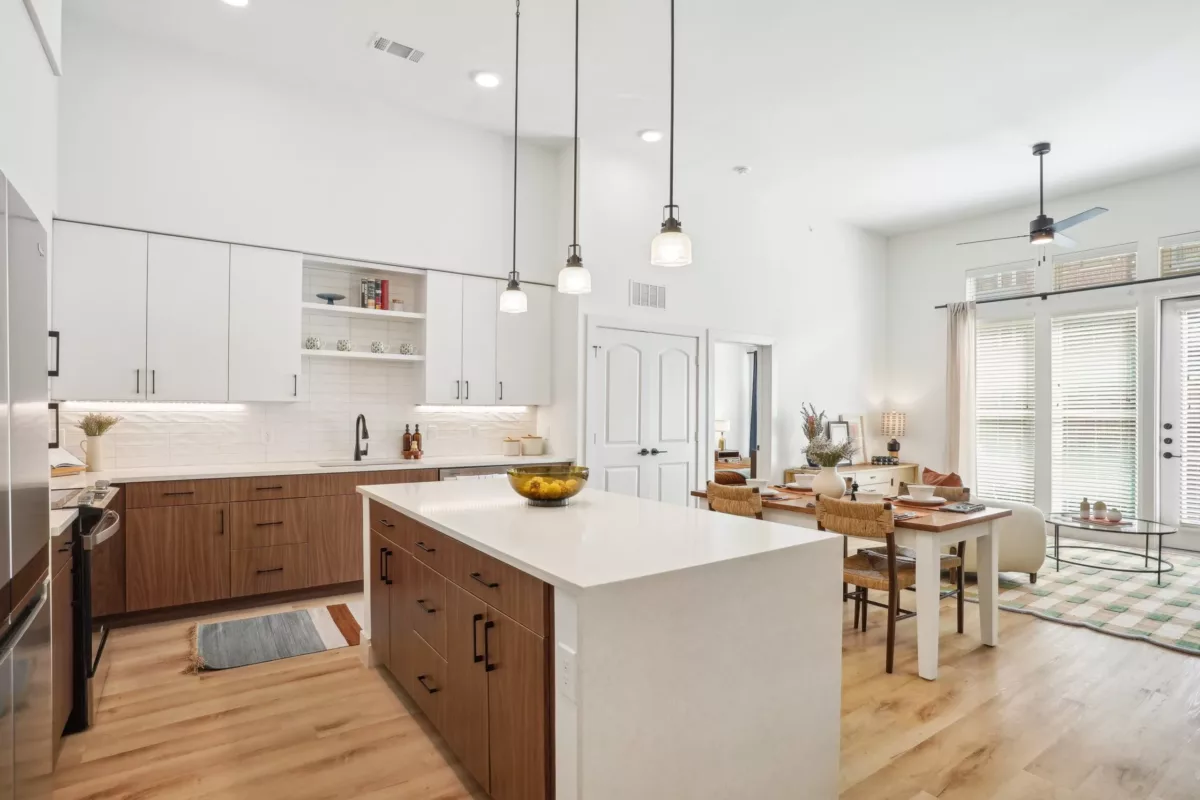Kitchen with white and brown cabinets, center island, and hanging pendant lights