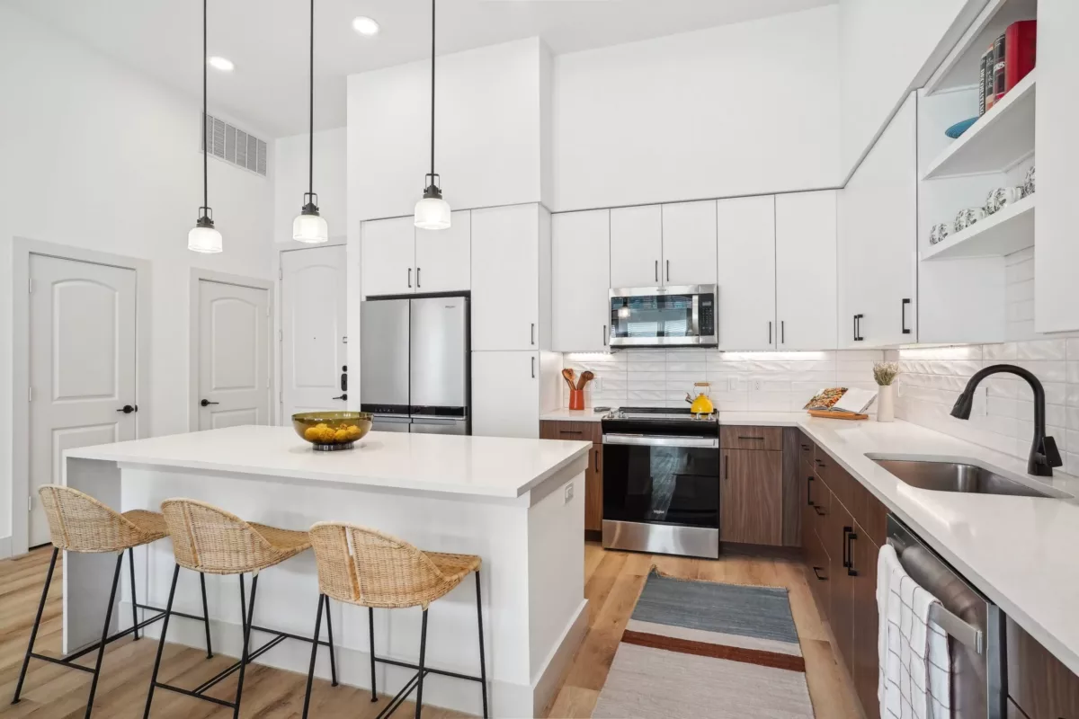 Kitchen with white and brown cabinets, center island, and hanging pendant lights