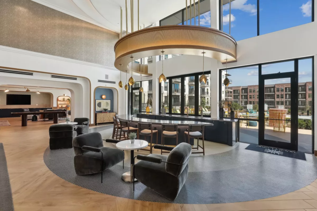 Elegant circular bar in an open lounge with sleek seating, overlooking an outdoor pool.