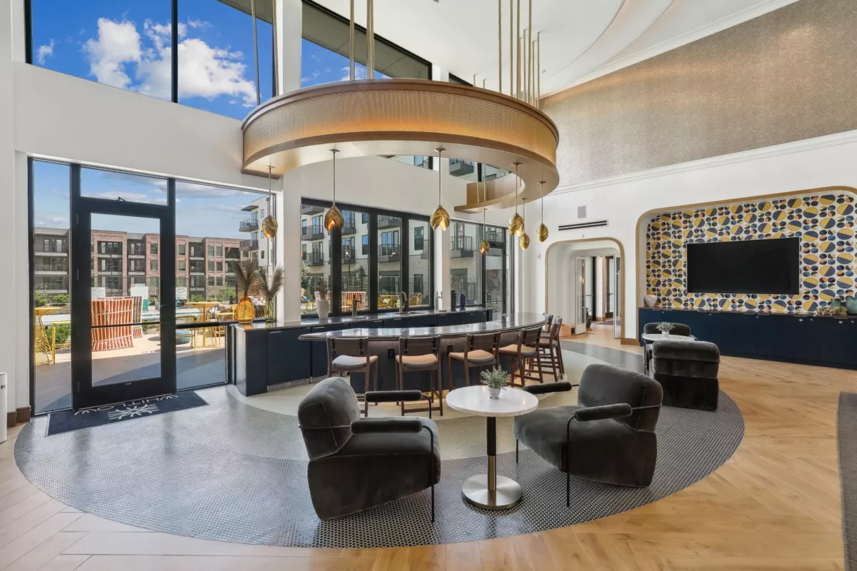 Upscale bar and lounge area with circular bar setup and chic furniture, overlooking a pool.