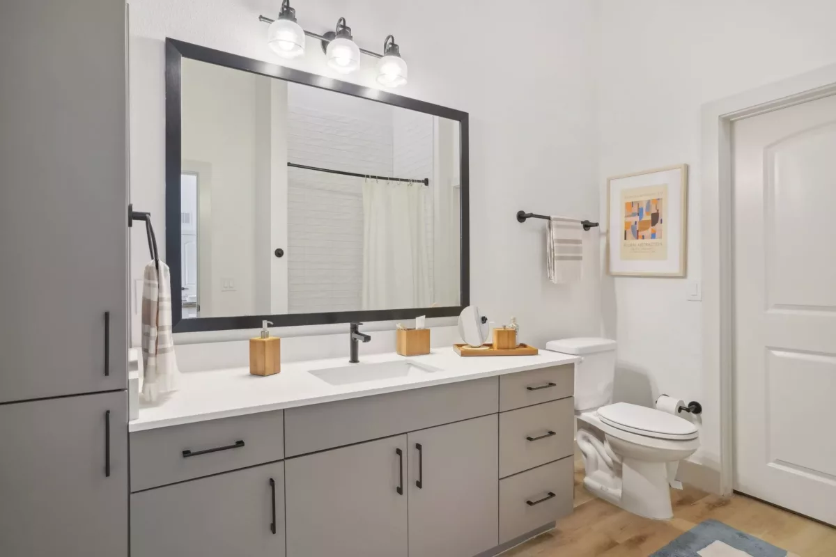Bathroom with large mirror and gray vanity with white countertop.