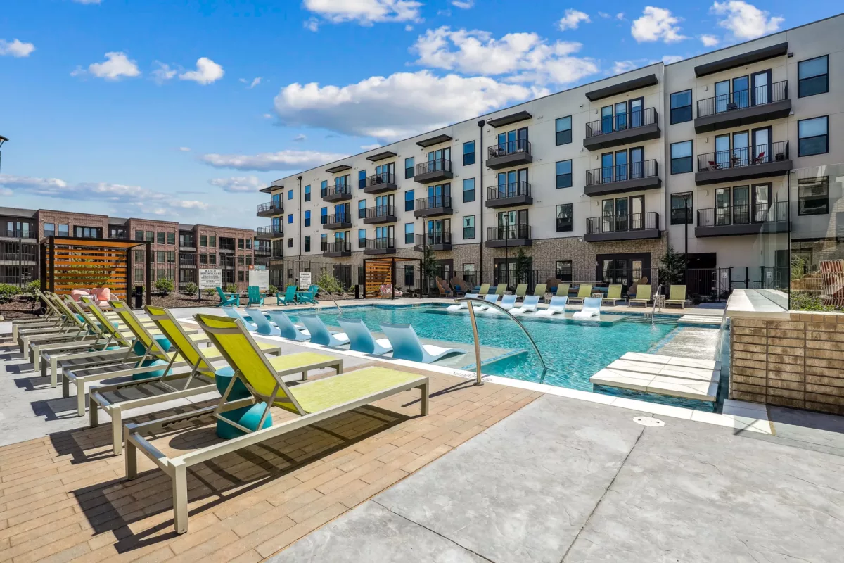 Vibrant poolside scene with colorful loungers, surrounded by stylish apartment buildings.