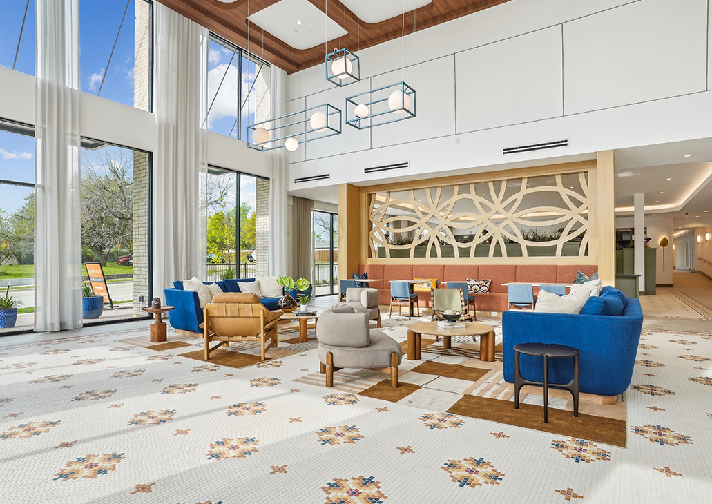 Lobby with two-story windows, tile floors with floral designers, and armchairs for seating
