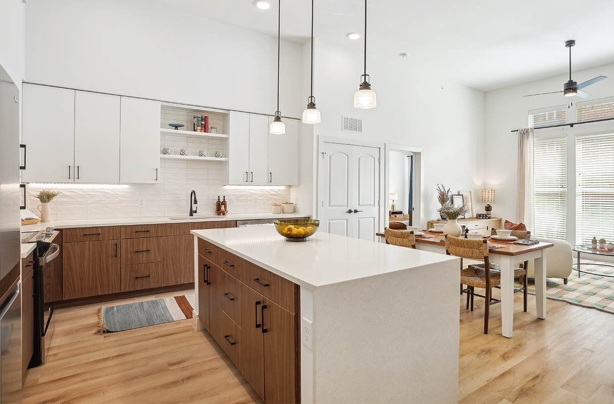 Kitchen with white and brown cabinets, center island, and hanging pendant lights